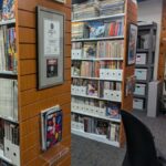 An image of the Video Game History Foundation's physical library, showing rows of bookshelves filled with old magazines, and a life-size statue of Lara Croft in the far right corner